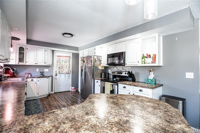 kitchen with a sink, dark countertops, appliances with stainless steel finishes, and white cabinetry