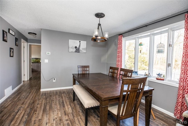 dining area featuring dark wood-style floors, visible vents, a textured ceiling, and baseboards