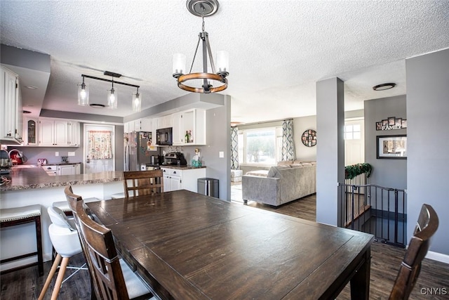 dining area featuring baseboards, dark wood-type flooring, a chandelier, and a textured ceiling