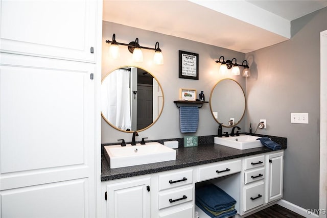 full bath with a sink, baseboards, and double vanity