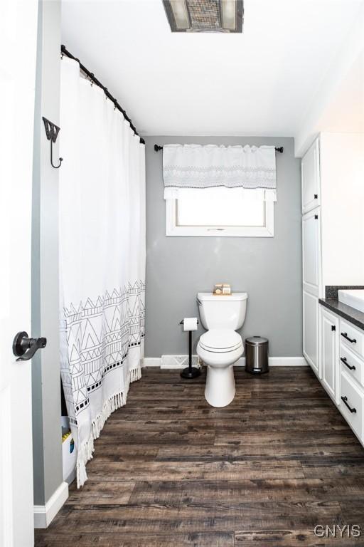 full bath with visible vents, a shower with shower curtain, baseboards, and wood finished floors