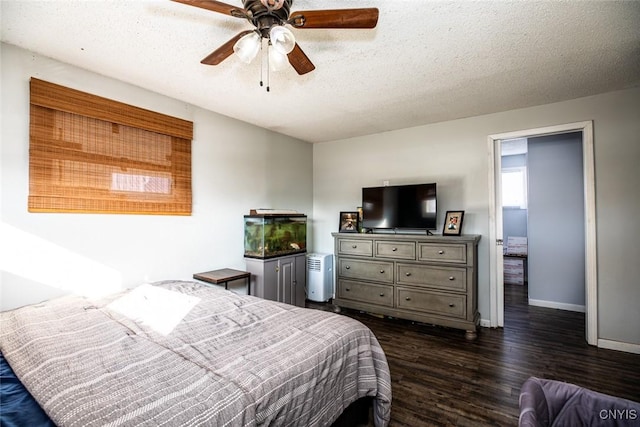 bedroom with dark wood finished floors, ceiling fan, baseboards, and a textured ceiling