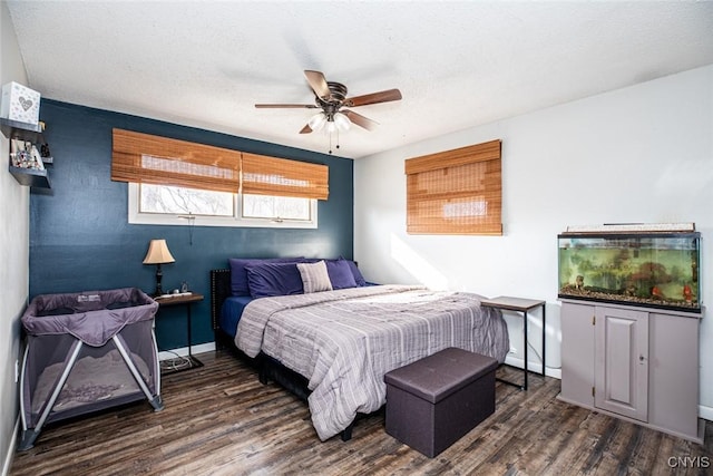 bedroom with ceiling fan, wood finished floors, baseboards, and a textured ceiling