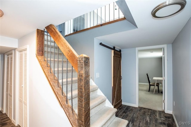 stairs featuring a barn door, baseboards, and wood finished floors