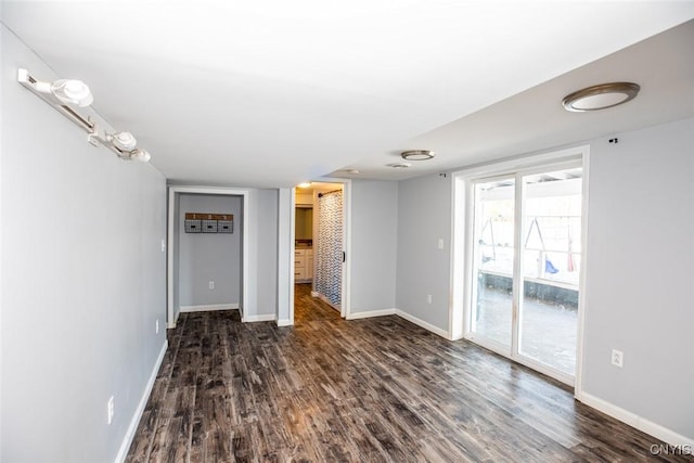 unfurnished living room featuring baseboards and dark wood-style flooring