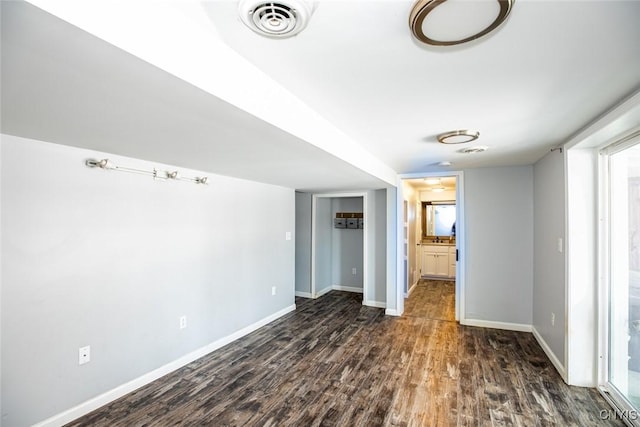 unfurnished room with visible vents, baseboards, and dark wood-style floors