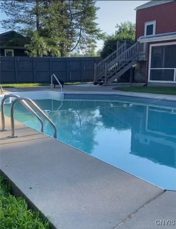 view of swimming pool featuring stairs, fence, and a fenced in pool