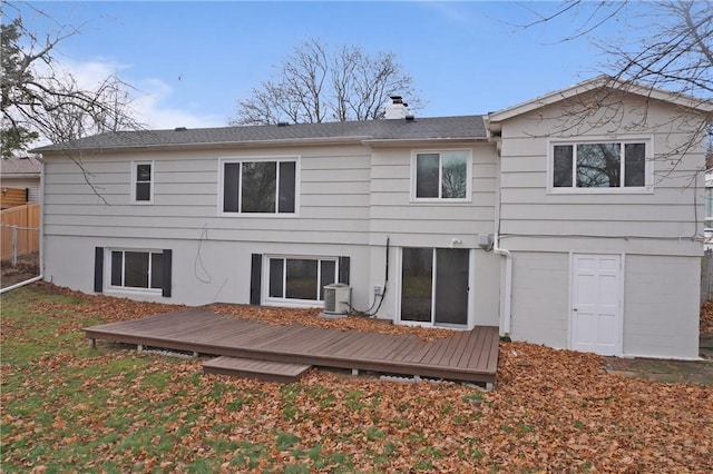 rear view of house featuring a deck, central air condition unit, a yard, and a chimney