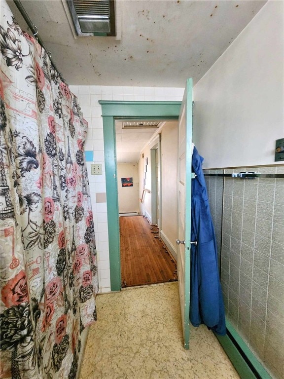 hallway featuring visible vents and tile walls