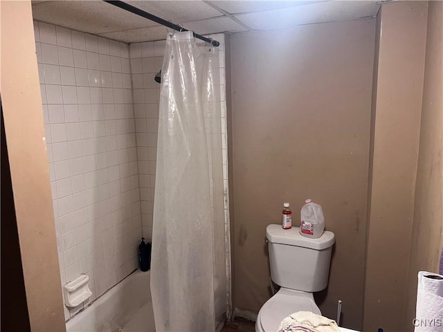 bathroom with a drop ceiling, toilet, and shower / tub combo