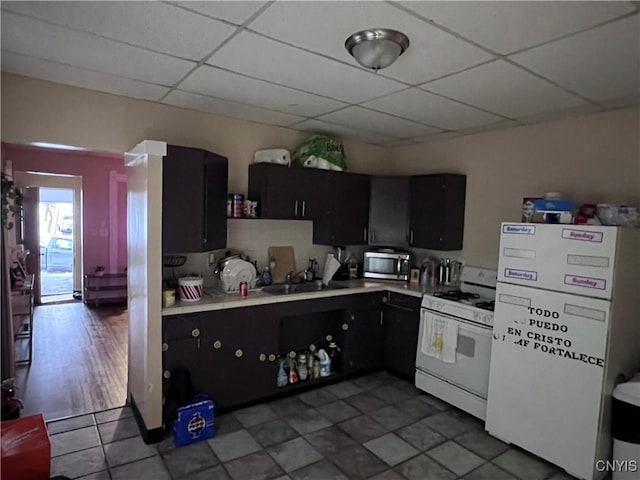 kitchen featuring a paneled ceiling, white appliances, dark cabinets, and light countertops