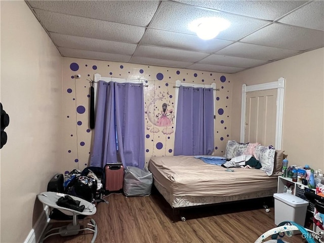 bedroom with a paneled ceiling and wood finished floors