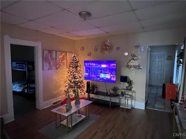 living area with wood finished floors, visible vents, a drop ceiling, and baseboards