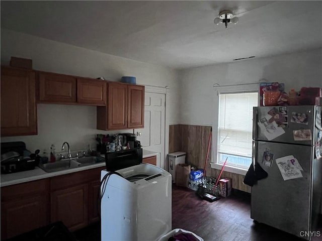 kitchen featuring light countertops, brown cabinets, freestanding refrigerator, washer / clothes dryer, and a sink