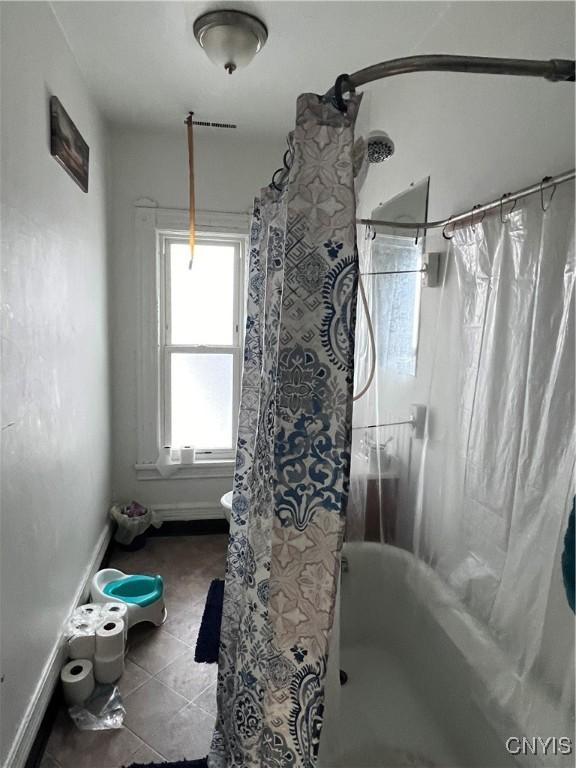 bathroom featuring tile patterned flooring, baseboards, and shower / bath combo with shower curtain