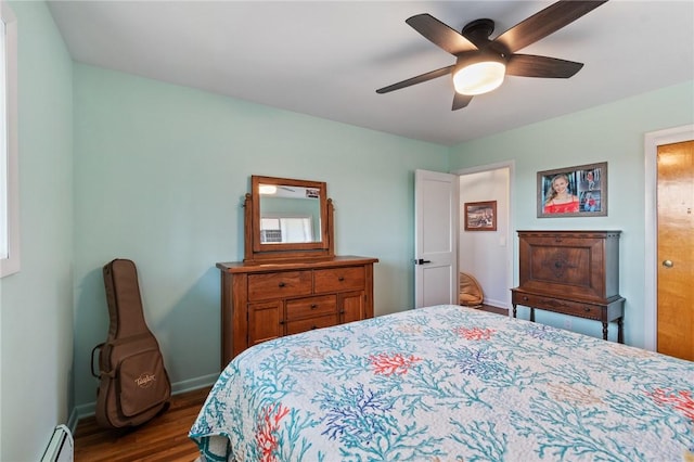 bedroom with a ceiling fan, a baseboard heating unit, baseboards, and wood finished floors