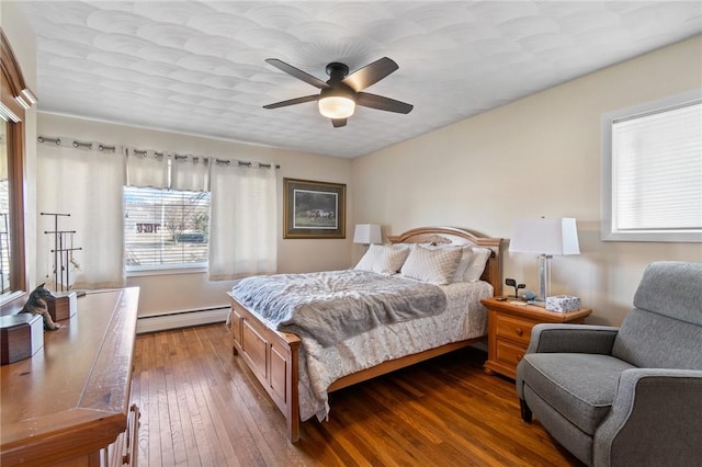 bedroom featuring ceiling fan, a baseboard heating unit, and dark wood finished floors