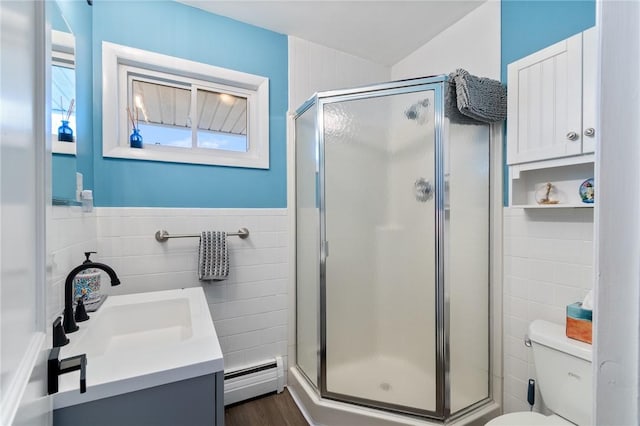 full bath featuring a baseboard heating unit, toilet, tile walls, and a shower stall