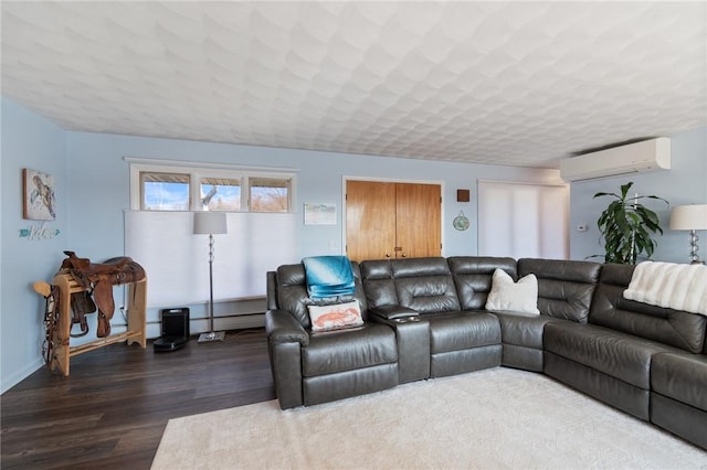 living area with a textured ceiling, a wall unit AC, and wood finished floors