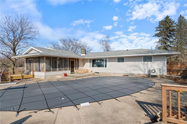 rear view of house with a patio area, a fenced in pool, a chimney, and a sunroom