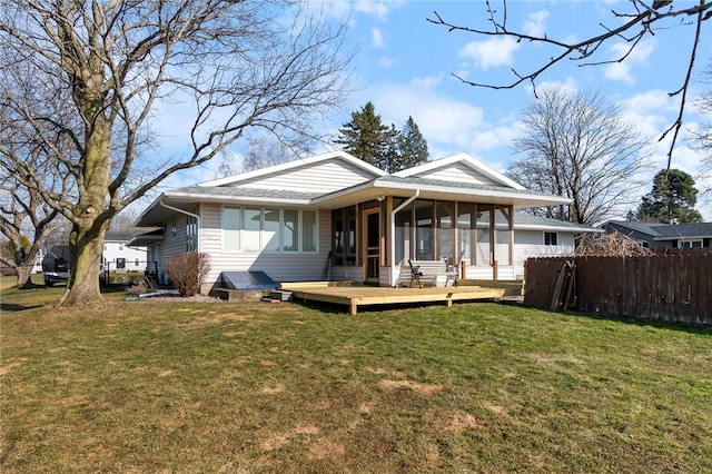 back of house featuring a lawn, a wooden deck, a sunroom, and fence