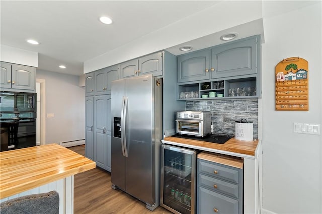 kitchen with tasteful backsplash, a baseboard heating unit, beverage cooler, butcher block counters, and black appliances