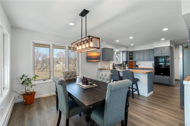 dining room with baseboard heating, recessed lighting, baseboards, and wood finished floors