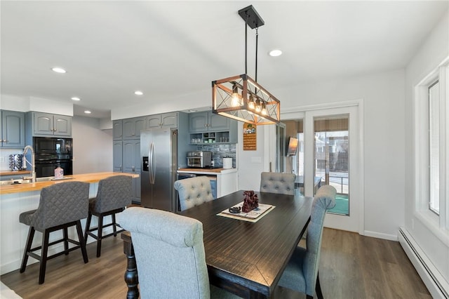 dining room featuring a baseboard radiator, plenty of natural light, and dark wood finished floors