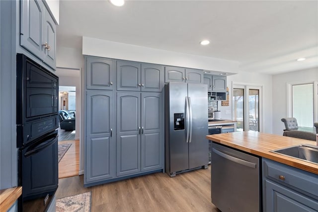 kitchen featuring light wood-style flooring, gray cabinets, appliances with stainless steel finishes, and butcher block countertops