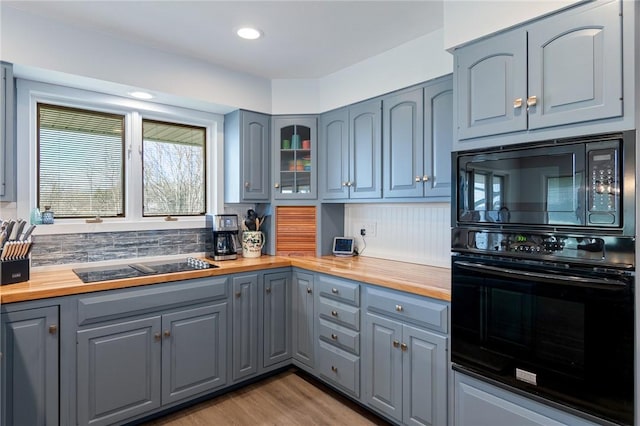 kitchen with black appliances, gray cabinets, light wood finished floors, and butcher block countertops