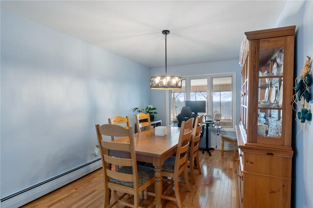 dining space with a notable chandelier, light wood finished floors, and a baseboard radiator