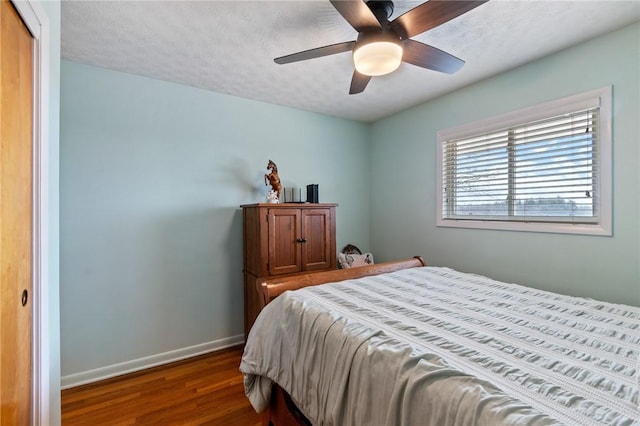 bedroom featuring a closet, baseboards, a textured ceiling, and dark wood finished floors