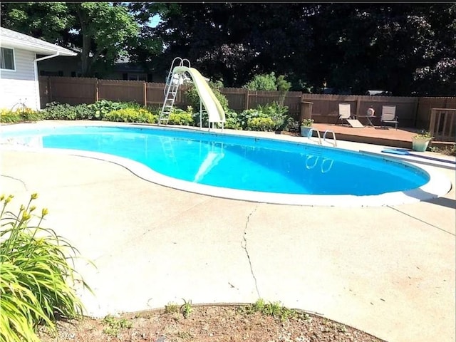 view of swimming pool featuring a patio area, a fenced backyard, a fenced in pool, and a water slide