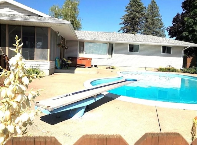 view of pool with a fenced in pool, a patio area, a diving board, and a sunroom