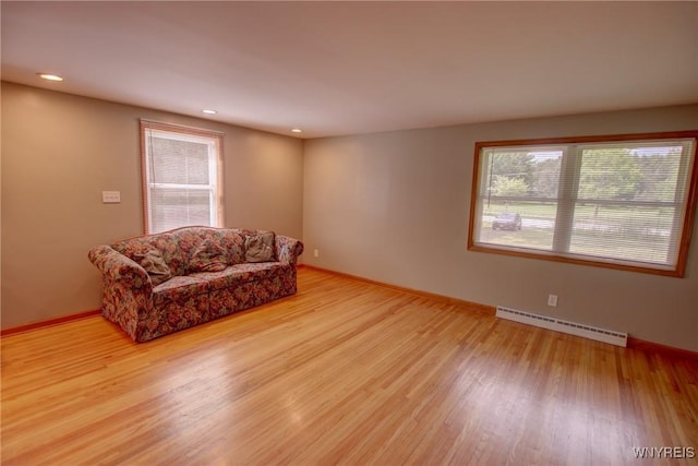 sitting room featuring a baseboard radiator, plenty of natural light, and light wood-style floors