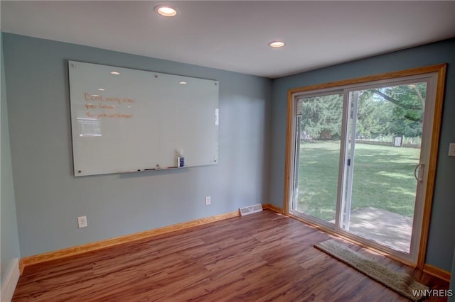 spare room featuring a wealth of natural light, visible vents, baseboards, and wood finished floors