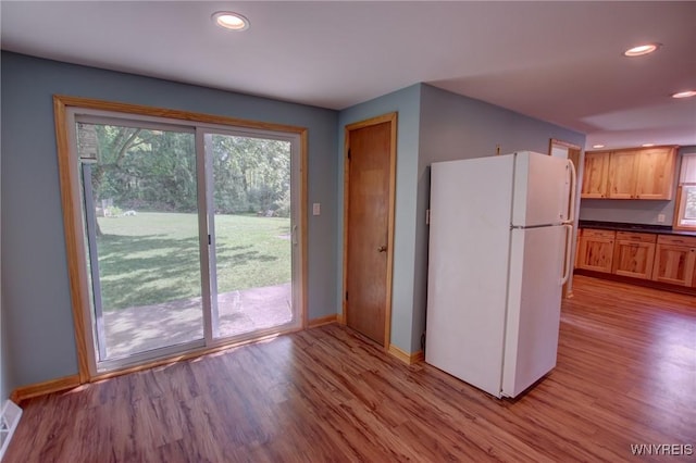 kitchen with baseboards, light wood-style flooring, recessed lighting, freestanding refrigerator, and dark countertops