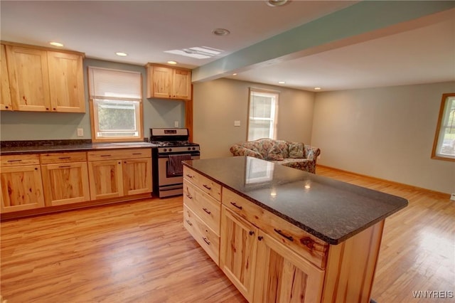 kitchen featuring recessed lighting, light brown cabinetry, light wood-style floors, gas range, and a center island