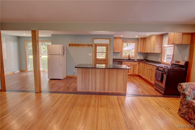 kitchen with light wood finished floors, gas stove, freestanding refrigerator, and a sink