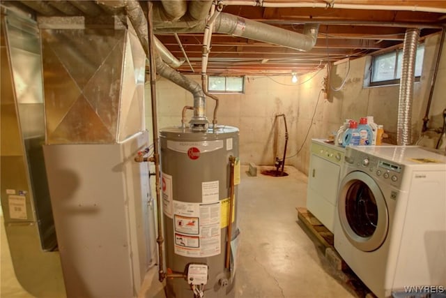 clothes washing area featuring heating unit, laundry area, gas water heater, and separate washer and dryer