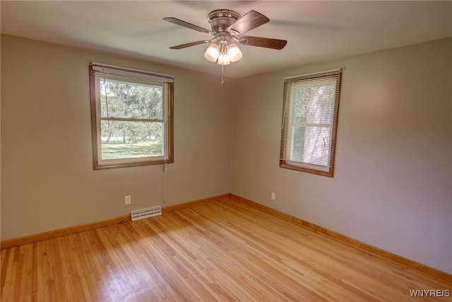 spare room featuring visible vents, baseboards, light wood-style flooring, and a ceiling fan