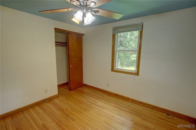 unfurnished bedroom with baseboards, a closet, light wood finished floors, and ceiling fan