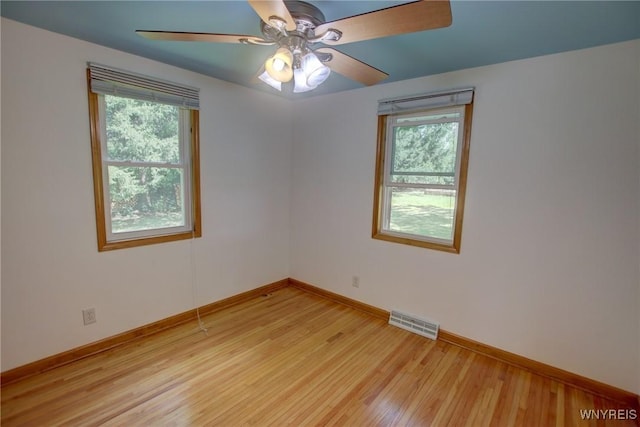 unfurnished room featuring a ceiling fan, baseboards, visible vents, and light wood finished floors