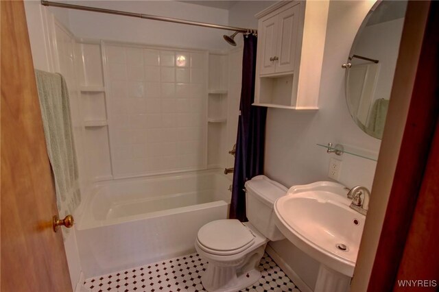 bathroom featuring toilet, shower / bath combo, and a sink