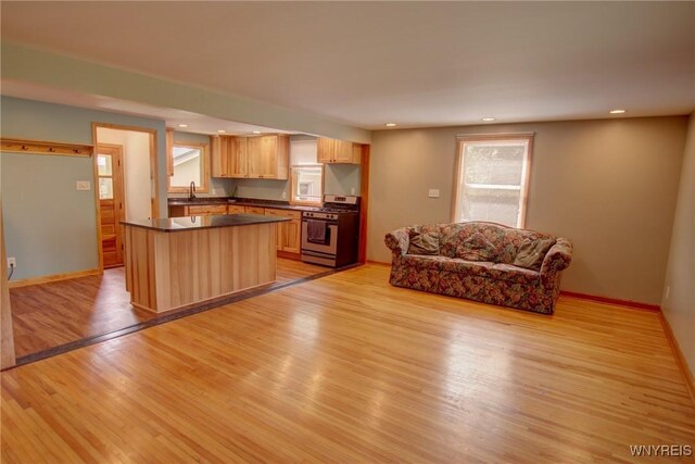 kitchen featuring dark countertops, recessed lighting, light wood-style floors, stainless steel gas stove, and a sink