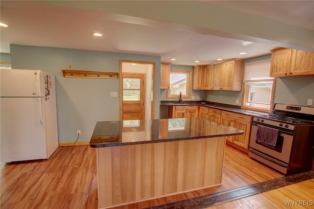 kitchen featuring a center island, stainless steel range with gas stovetop, recessed lighting, freestanding refrigerator, and light wood-style floors