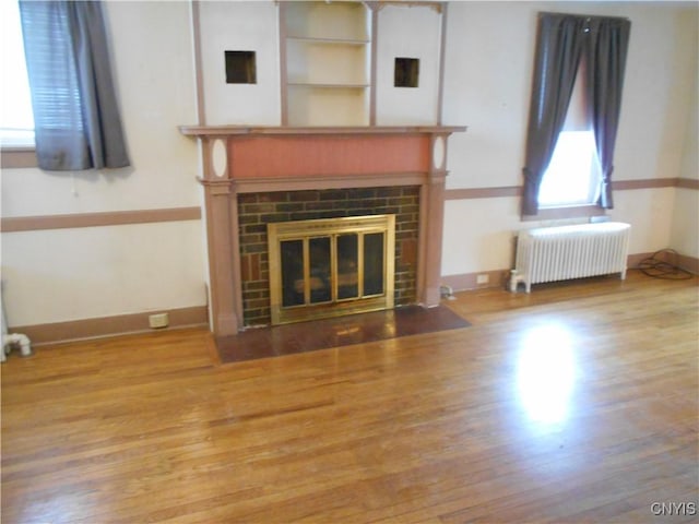 32 Fenner St, Cazenovia, NY 13035 - unfurnished living room featuring radiator, a fireplace, baseboards, and wood finished floors