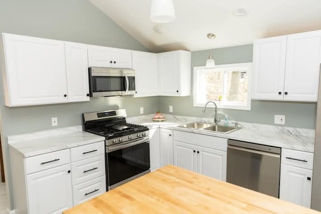 kitchen with pendant lighting, a sink, white cabinetry, stainless steel appliances, and lofted ceiling