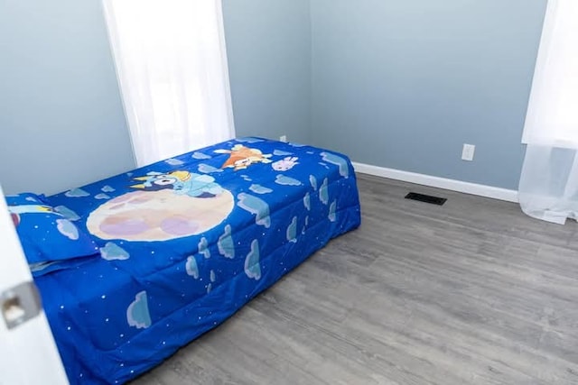 bedroom with visible vents, baseboards, and wood finished floors