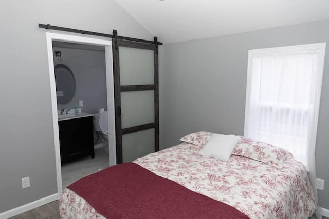 bedroom with a barn door, multiple windows, baseboards, and vaulted ceiling